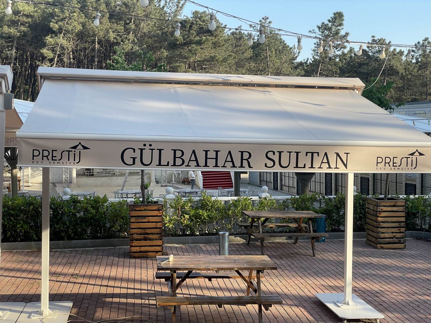 Saçağında işletme adı yazan krem brandalı şemsiye