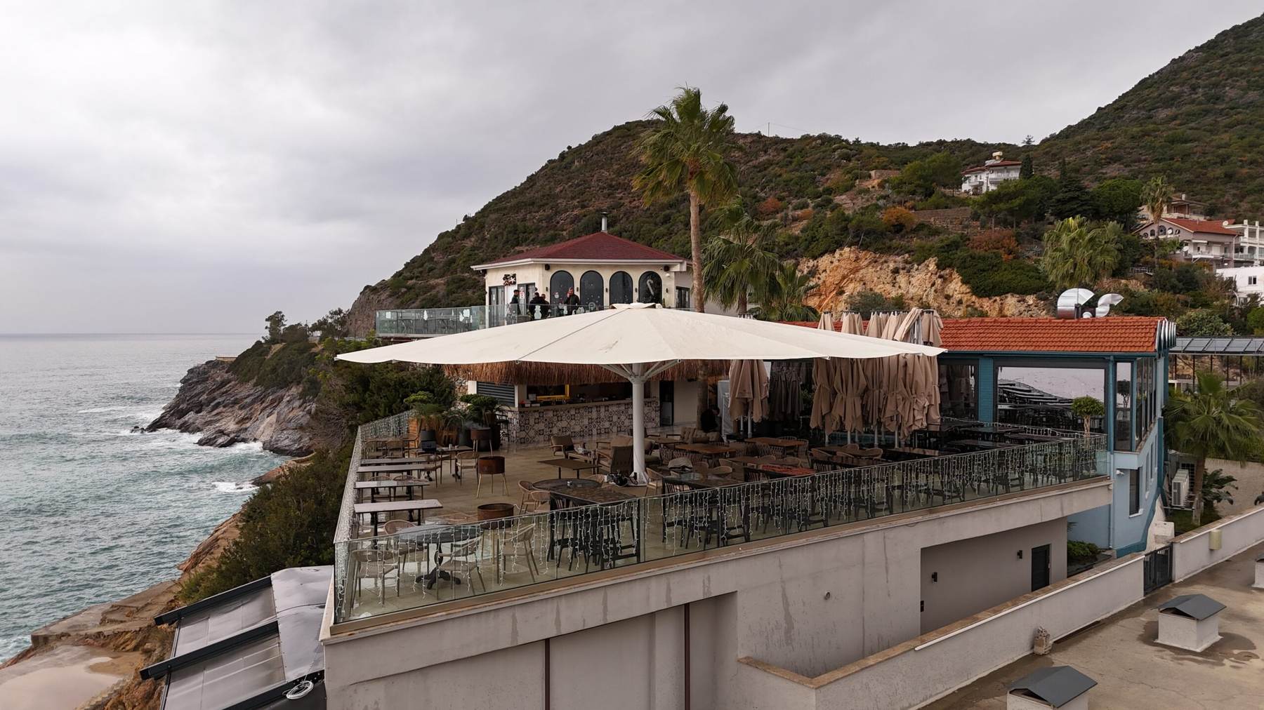Kayalık sahil üzerinde teras restoranı ve açık dev şemsiye
